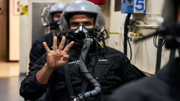 Axiom-4 crew member Shubhanshu Shukla in a flight suit, aviation helmet and oxygen mask, gesturing to the camera during training at Nasa's Johnson Space Center (JSC) in Houston, Texas. Astronaut Shubhanshu Shukla soars into space June 2025 as the first Indian to join the International Space Station, bearing with him New Delhi's dreams of its own manned space flight. File image/AFP | Firstpost