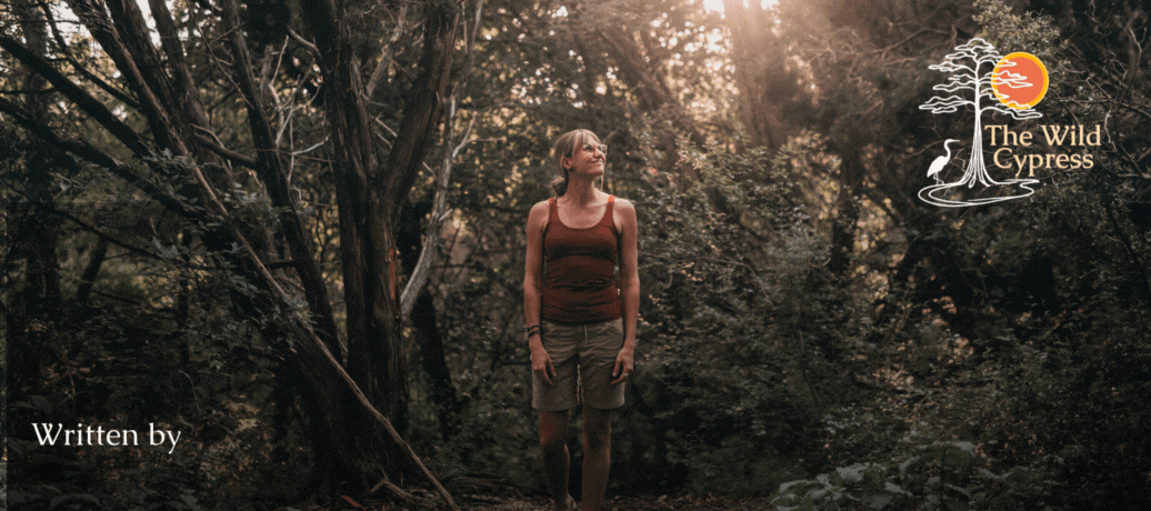 [image: Summer is standing in a dense forest, wearing a red tank top and khaki shorts. They are looking to their left, a calm smile on their face. Sunlight is streaming through.]