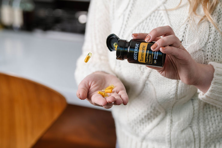 Mujer manipulando un frasco de cápsulas de cúrcuma