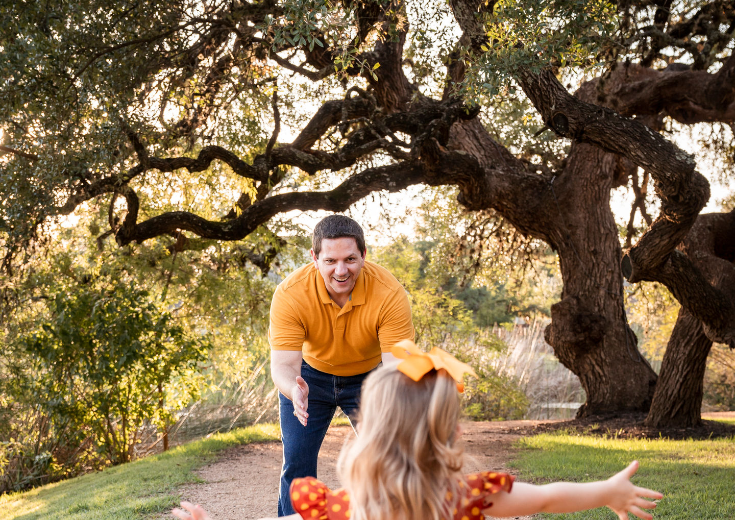 Young daughter running into father’s arms during candid family photography session in Dripping Springs.