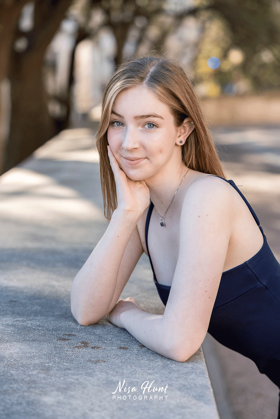 Close-up senior portrait of a blue-eyed girl with a natural dimpled smile, styled for a refined and modern look.