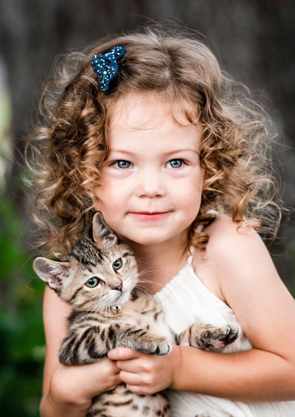 Young girl cuddling with family dog during outdoor family session in Dripping Springs, Texas.
