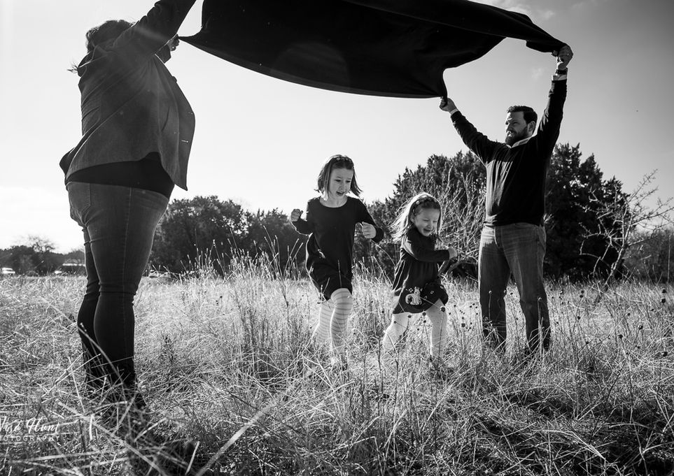 Family laughing and playing together during candid outdoor family photography session in South Austin.