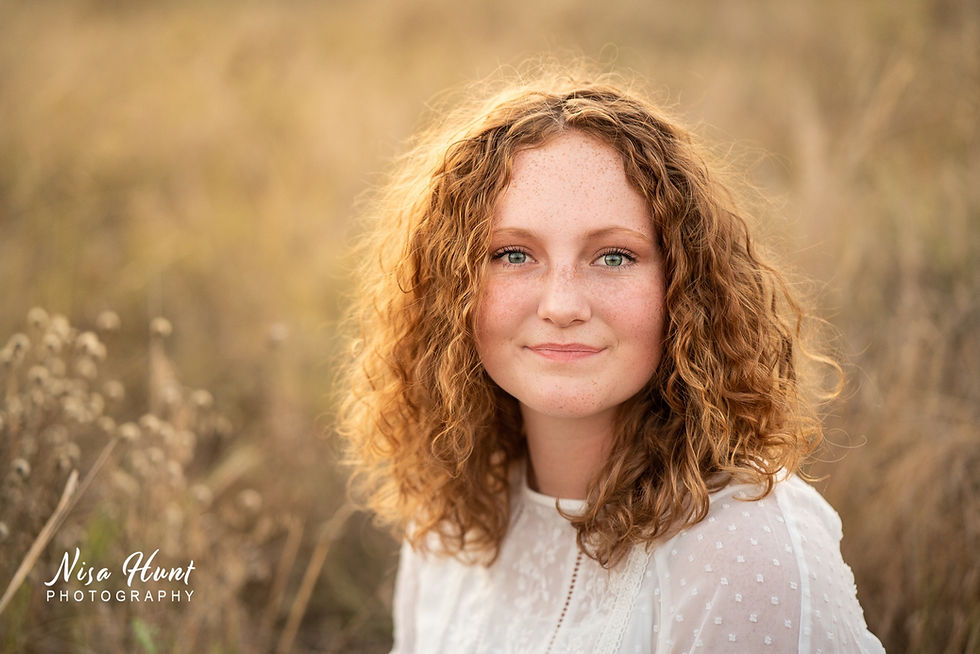 Senior portrait in dripping springs texas with a female in a field of tall grasses in golden hour.