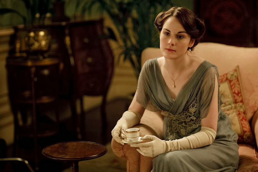 Lady Mary exhibiting a "no no" in glove etiquette in this scene from Downtown Abbey. Proper glove etiquette suggests gloves off when eating and drinking. Photo courtesy of Etiquette with Maura Graber.