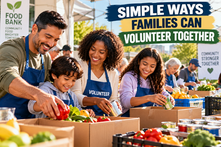 Multiracial family packing fresh produce and canned food together at a community food bank volunteer event.