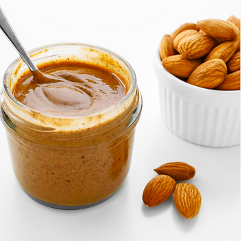 Jar of almond butter with spoon, next to a white bowl of whole almonds on a clean, white background. Smooth and creamy texture.