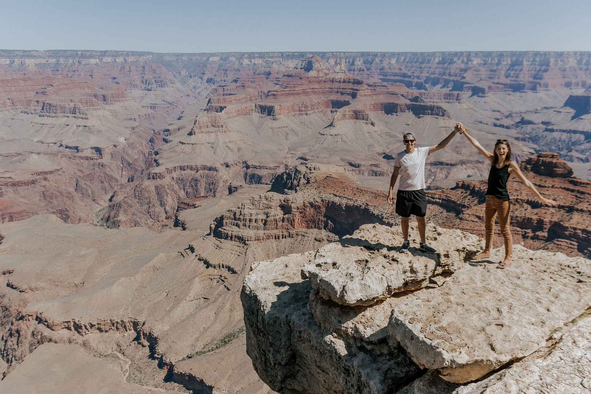 couple holding up hands by the grand canyon