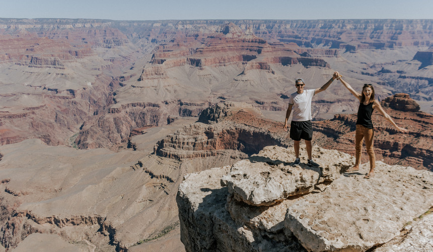 couple holding up hands by the grand canyon