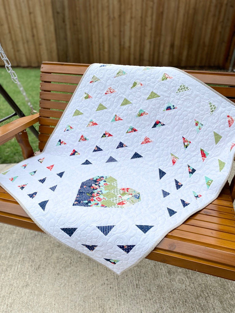 Thumbnail: White quilt with colorful triangles and bee design on wood swing