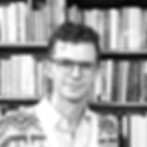 Black and white professional photo of a man (Mariano Echeverria) standing against a bookcase.