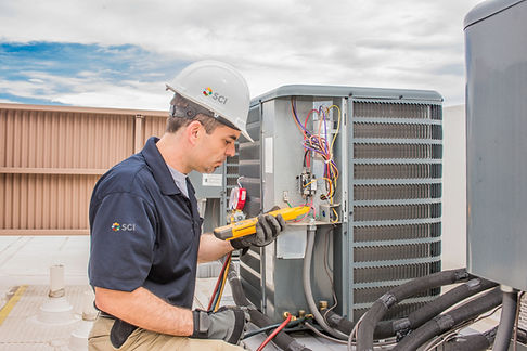 Trained hvac technician holding a voltage meter, performing preventative maintenance on a