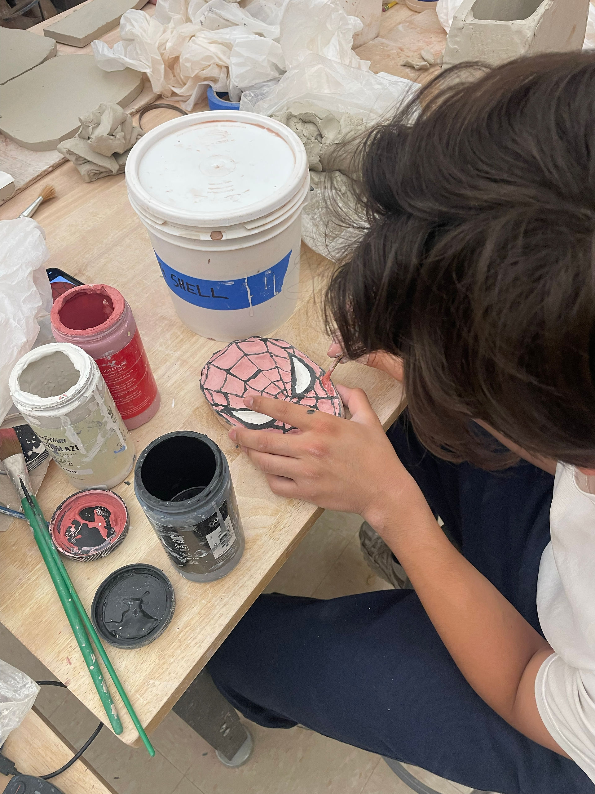 Student working on slab paint palette of Spiderman