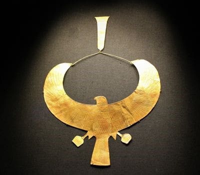 A gold necklace shaped like a hawk.