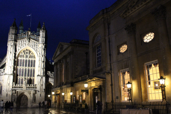 Bath Abbey and the Roman baths lit up at night.