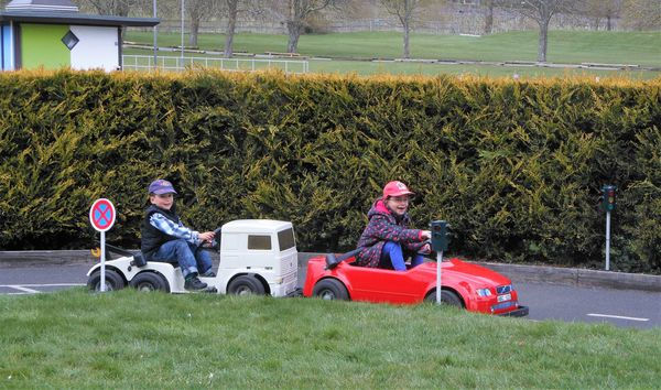 Kids on a driving track in toy cars