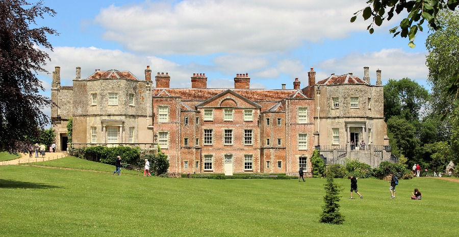 People walking on the frot lawn with Mottisfont House in the background
