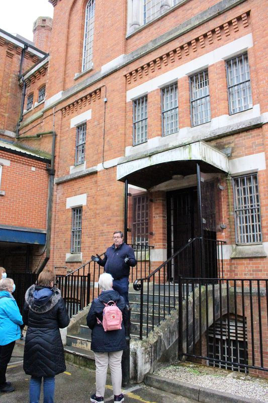A man standing on steps of Dorchester Prison talking to a tour group
