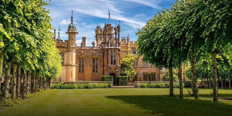 Knebworth House Gothic Tudor mansion seen through tree-lined grounds on a sunny day, used as the hero image for the Knebworth House ongoing design support case study by Julie Nicholls