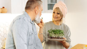 A woman making a bid for her husband's attention by offering him a taste of food.