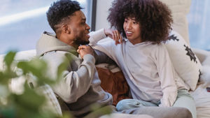 A couple laughs on a cozy couch.