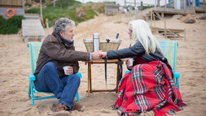 A couple sitting on a beach discussing life dreams.