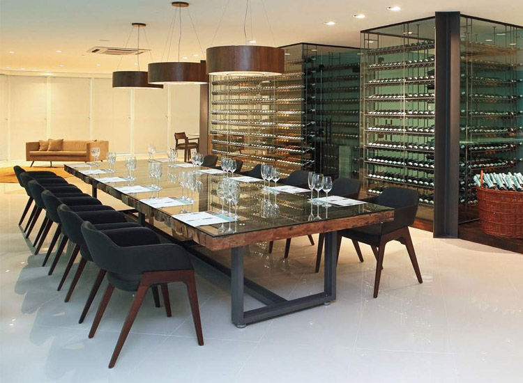 Miniatura: Mesa de jantar comprida com cadeiras escuras e adega de vinhos.