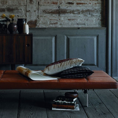 Miniatura: Elegante daybed de couro marrom com almofadas e livros em casa rústica.