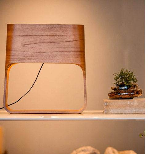 Miniatura: Luminária de mesa moderna com topo de madeira e base clara, acesa em prateleira.