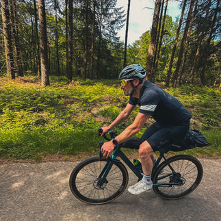 cyclist riding on road through the forest