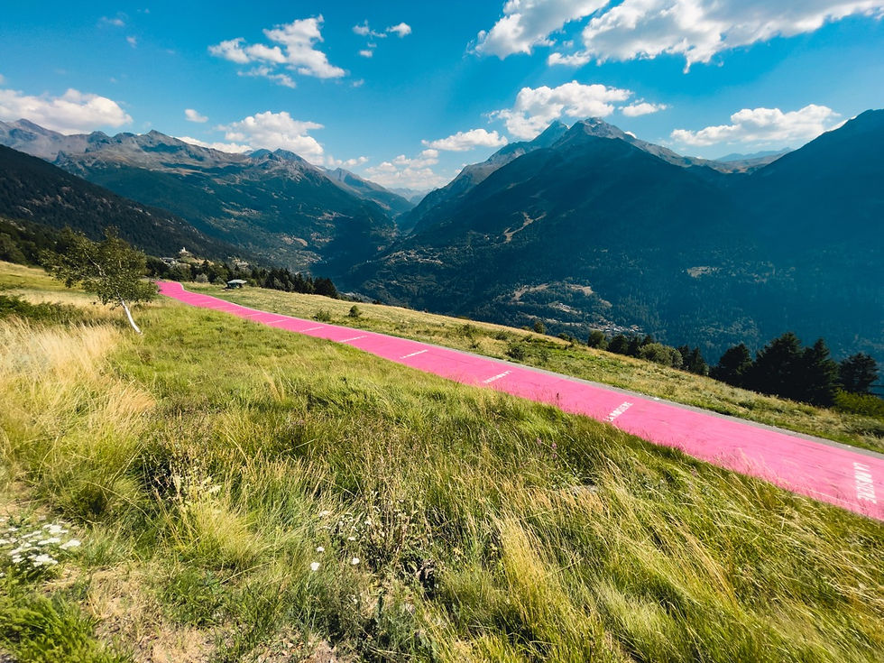 a pink painted road climbing above the valley below