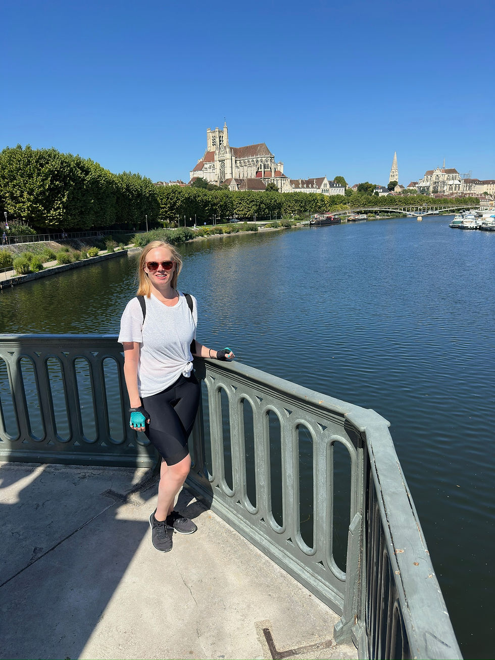 woman standing on bridge overlooking Auxerre with a river and cathedral in the background
