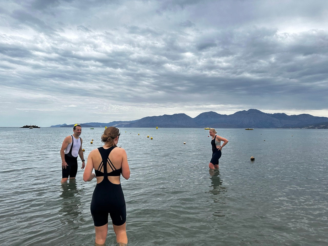 2 women and 1 man standing in the ocean in cycling bibs