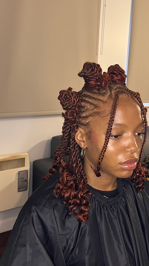 Woman with detailed braided hairstyle, brown hair and Munabraids in a salon.