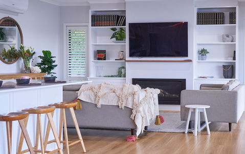 Looking onto the main living area with kitchen island bench, lounge and gas fireplace.