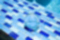 Close-up of a pool corner with a clear glass orb on blue and white mosaic tiles, reflecting the glistening pool water and enhancing the aquatic aesthetic.