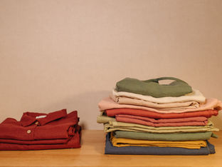 Stapel gevouwen kleding op een tafel in warme tinten.