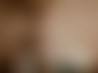 Eine Frau (Désirée Tobler) sitzt unscharf im Hintergrund auf einem weißen Stuhl und hält eine Tasse in den Händen. Im Vordergrund steht ein Glas mit weißen Rosen auf einem Tisch, daneben liegen ein Notizbuch und ein Stift.