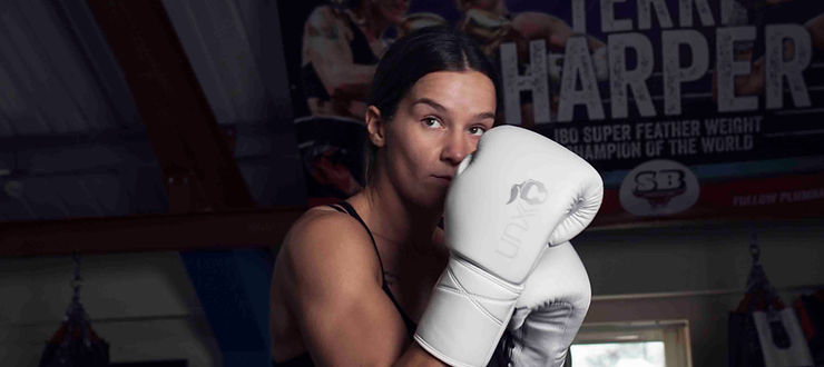 WBA Super Welterweight World Champion Terri Harper posing with white Unorthodoxx gloves.