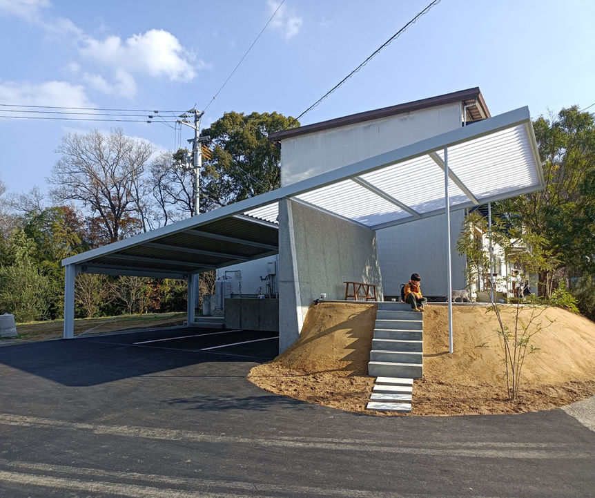 カーポートと建物の外観、階段に座る人