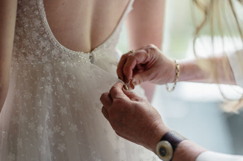 Brautmutter macht das Brautkleid zu