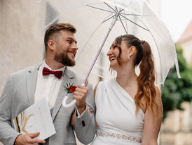 Hochzeitsfotos bei Regen mit lachendem Brautpaar unter transparentem Regenschirm bei Dresden