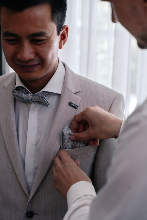 Trauzeuge steckt das Anstecktuch beim Bräutigam in den Anzug