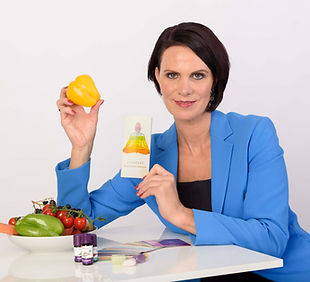 Ganzheitliche Farbberatung: Frau in blauem Blazer präsentiert Farbpaletten, auf dem Tisch steht eine Schüssel mit buntem Gemüse