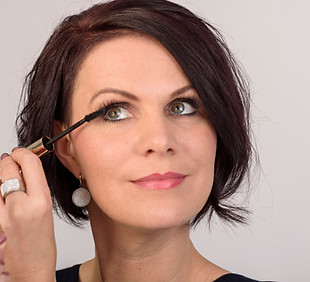 Schmink-Workshop: schön geschminkte Frau benutzt Wimperntusche