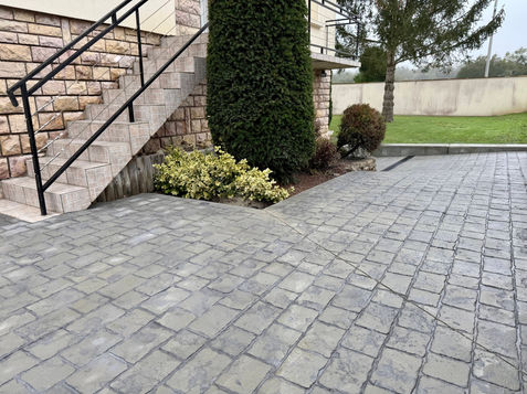Une belle entrée de propriété avec un revêtement de sol Béton Décoratif pavés gris.