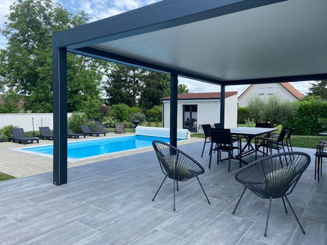 Aménagement réalisé par notre société La Batisse avec Piscine Wide 75 Bleue Mon de Pra, réalisation d'un Béton Décoratif autour de la piscine imitation pavés à l'ancienne et installation d'un volet hors-sol blanc.