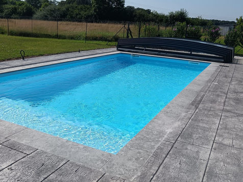 Abri de piscine Néo 30 replié en bout de piscine.