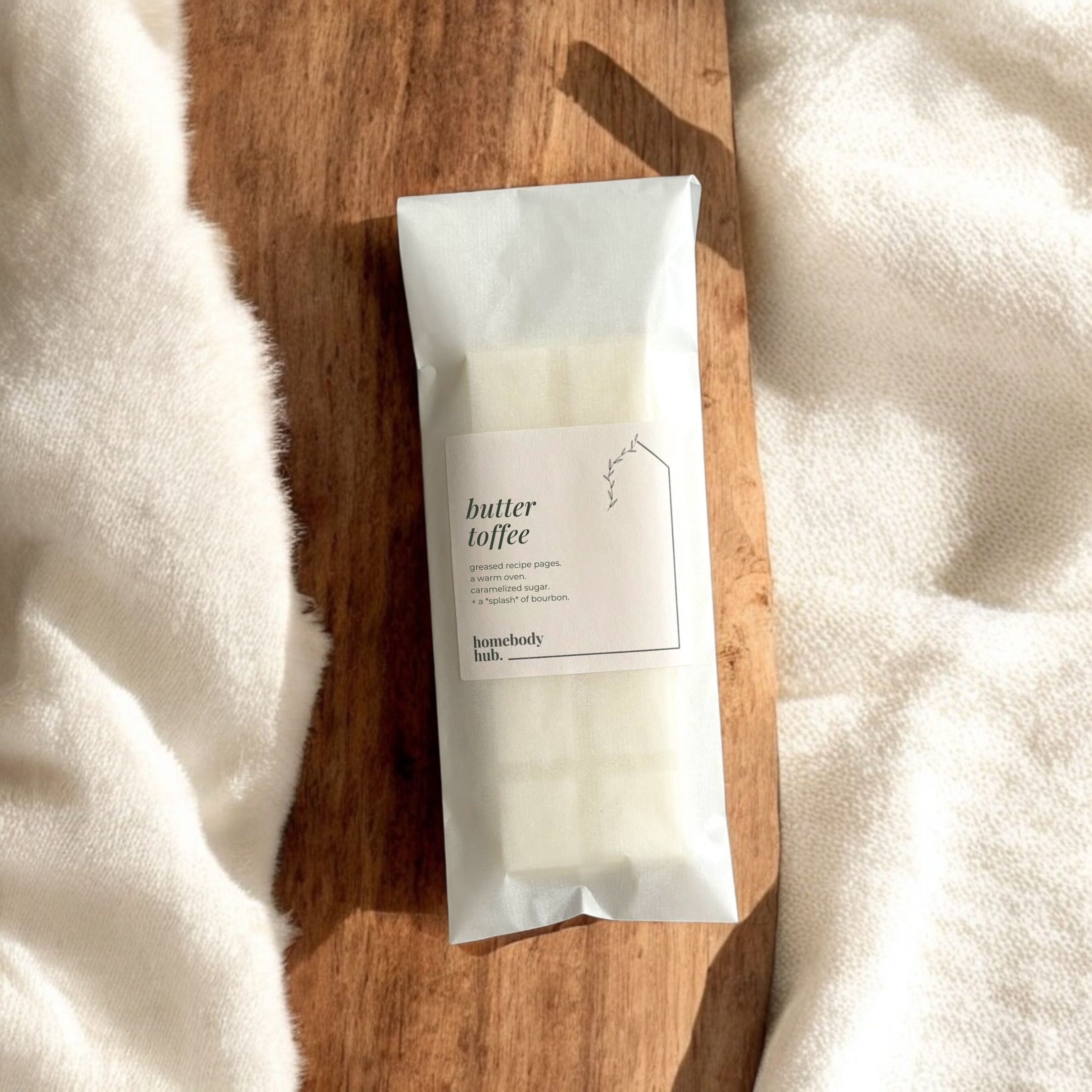 butter toffee wax melt snap bar on a wooden tabletop with a cream colored blanket.