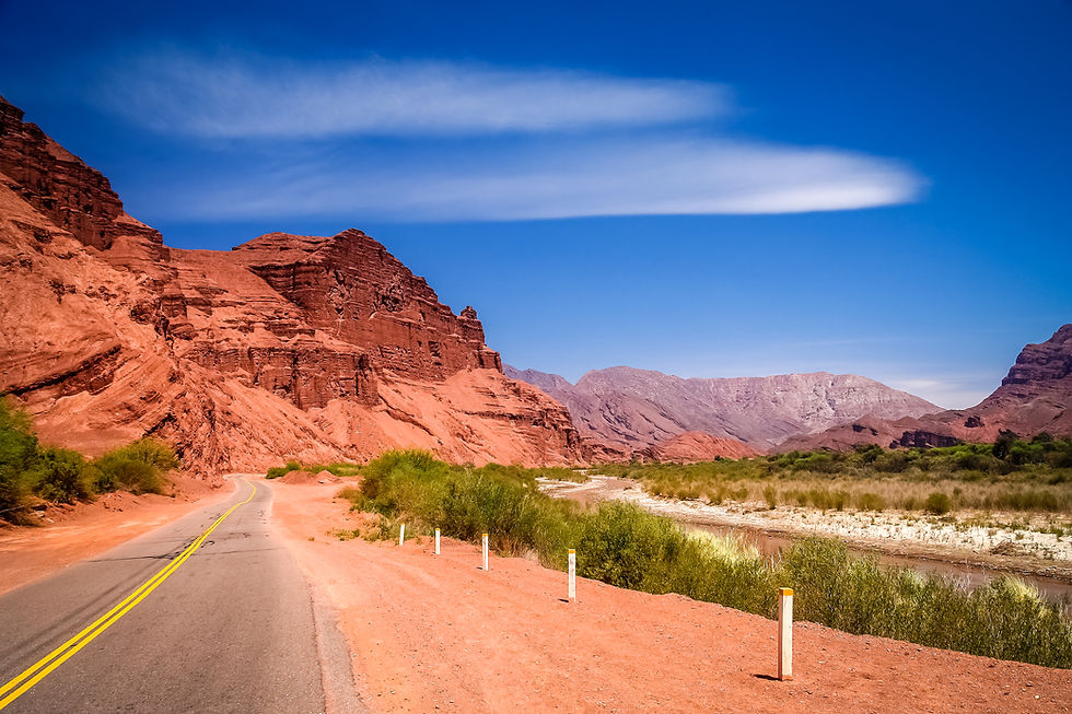 Ruta escénica en Cafayate rodeada de formaciones montañosas rojas en Salta